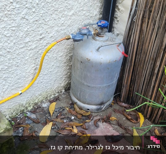 בלון גז עם צינור צהוב מחובר לקיר